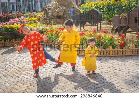 Children dancing happy laughing/HoChiMinh, Vietnam â?? February 13th 2015: The three kids wear "Ao dai". "Ao dai" is traditional clothes of Viet Nam. They dance to welcome a New Year