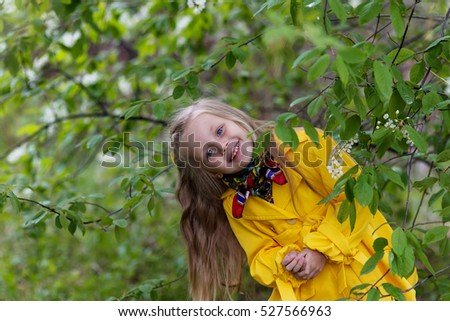 cheerful girl in a yellow raincoat on a sunny spring day