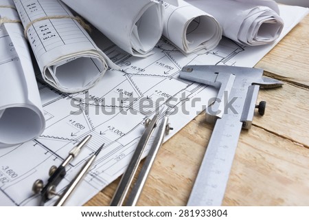 Architectural project, blueprints, blueprint rolls and divider compass, calipers on vintage wooden background. Construction concept. Engineering tools. Copy space
