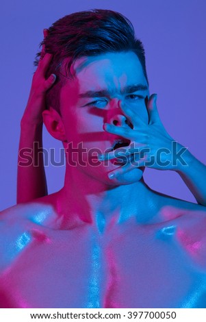 Beautiful athletic bodybuilder male model posing in studio. Muscular healthy sexy body. Expression on camera. Mixed light.
