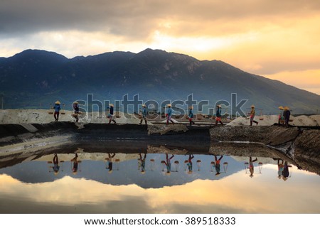 Ninh Thuan Province, Vietnam - February 28, 2016 :the women are working on salt field at dawn. Salt field Hon Khoi in Nha Trang, Viet Nam. Workers transporting salt from the fields Hon Khoi, Viet Nam.