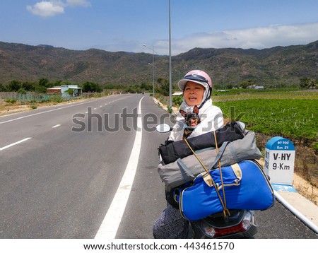 Vinh Hy town, Ninh Thuan province, VietNam - March 26, 2016 : woman resting with pet dog chihuahua after a long trip picnic by motorcycle