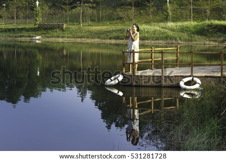 Flamingo Dai Lai, Vinh Phuc province, Vietnam - October 13, 2016 :woman standing on the dock watching the beautiful landscape of the autumn to take pictures, at Flamingo resort Dai Lai, Vietnam