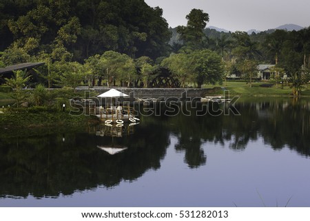 Flamingo Dai Lai, Vinh Phuc province, Vietnam - October 12, 2016 : table and chairs on wooden pier on shore of lake in summer landscape at Flamingo resort Dai Lai, Vietnam