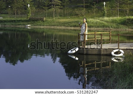 Flamingo Dai Lai, Vinh Phuc province, Vietnam - October 13, 2016 :woman standing on the dock watching the beautiful landscape of the autumn to take pictures, at Flamingo resort Dai Lai, Vietnam