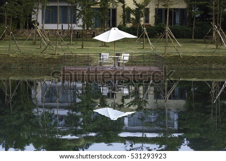 Flamingo Dai Lai, Vinh Phuc province, Vietnam - October 13, 2016 : lone wooden chairs sitting on the dock with a lake and cottages across