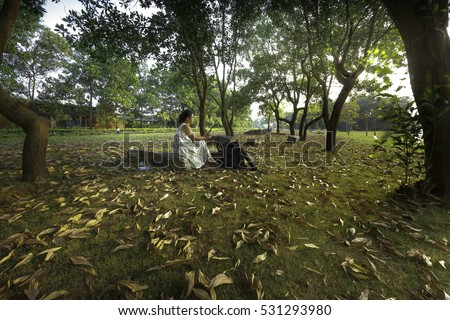 Flamingo Dai Lai, Vinh Phuc province, Vietnam - October 13, 2016: woman sitting reading relaxing on the lawn full of yellow leaves falling off into the sunset