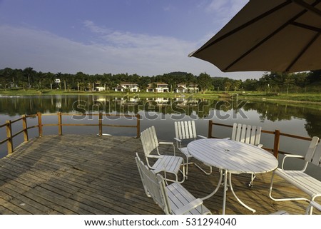 Flamingo Dai Lai, Vinh Phuc province, Vietnam - October 13, 2016 : table and chairs on wooden pier on shore of lake in summer landscape at Flamingo resort Dai Lai, Vietnam