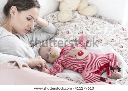 Shot of a young woman looking at her sleeping baby