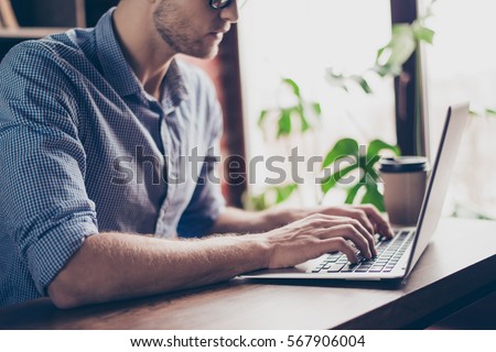 Close up of young busy man writing new book on laptop.