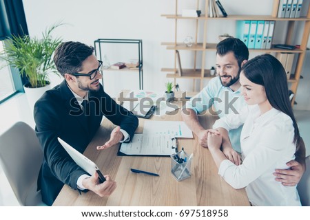 Side profile high angle shot of a deal between married couple and a salesman, consultating them about buying a purchase, all are dressed in formal outfits, smiling