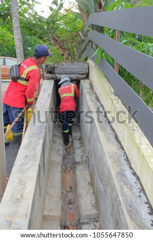 Muadzam Shah, Malaysia - March 22nd, 2018: Municipal workers "Alam Flora" uses sweepers and shovels to clean the garbage in the drain and put into the garbage bag.
