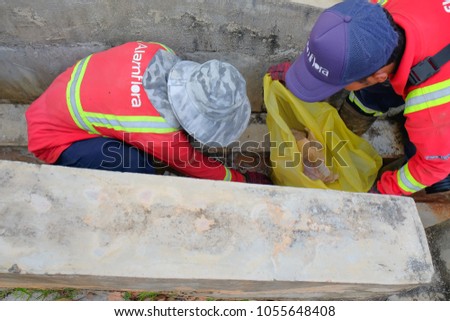 Muadzam Shah, Malaysia - March 22, 2018: Municipal workers "Alam Flora" uses sweepers and shovels to clean the garbage in the drain and put into the garbage bag.
