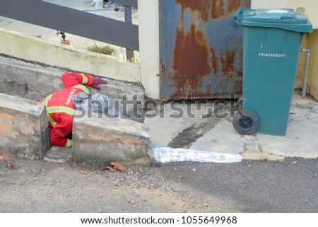 Muadzam Shah, Malaysia - March 22nd, 2018: Municipal worker "Alam Flora" uses sweepers and shovels to clean the garbage in the drain and put into the garbage bag.