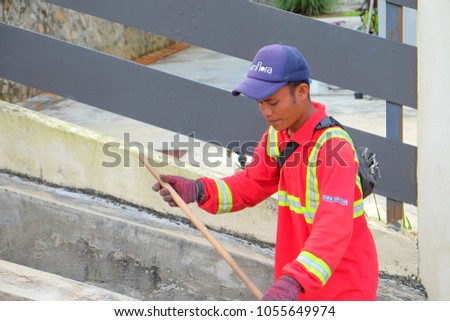 Muadzam Shah, Malaysia - March 22nd, 2018: Municipal worker "Alam Flora" uses sweepers and shovels to clean the garbage in the drain and put into the garbage bag.
