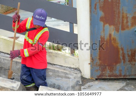 Muadzam Shah, Malaysia - March 22nd, 2018: Municipal worker "Alam Flora" uses sweepers and shovels to clean the garbage in the drain and put into the garbage bag.