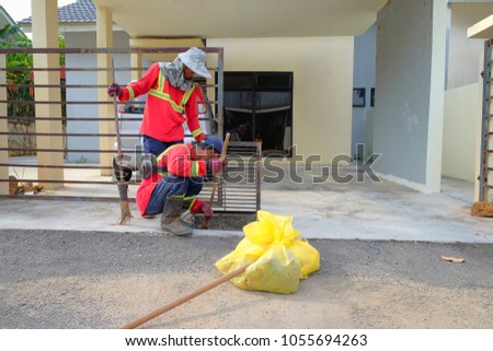 Muadzam Shah, Malaysia - March 22nd, 2018: Municipal workers "Alam Flora" uses sweepers and shovels to clean the garbage in the drain and put into the garbage bag.