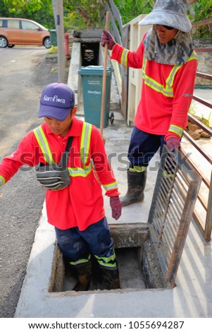 Muadzam Shah, Malaysia - March 22nd, 2018: Municipal workers "Alam Flora" uses sweepers and shovels to clean the garbage in the drain and put into the garbage bag.