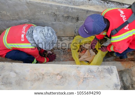 Muadzam Shah, Malaysia - March 22nd, 2018: Municipal workers "Alam Flora" uses sweepers and shovels to clean the garbage in the drain and put into the garbage bag.