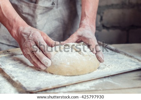 Wheat bread to the oven. The Baker's hands. Process the dough for wheat bread. Rustic style. Selective focus