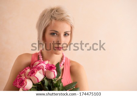 Young beautiful woman holding bouquet of pink roses. She is very satisfied. Valentine's day or international women's day celebration.