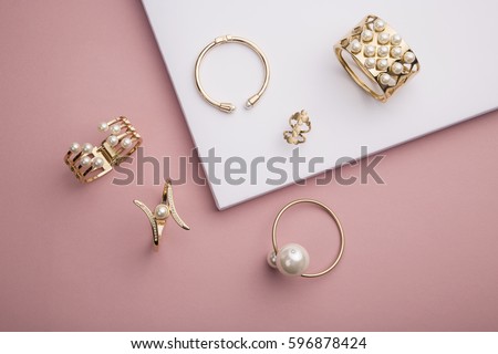 Pearl Golden Bracelets and ring on pink background - Pearl Bracelets on paper background setup