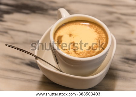 Top view a cup of Giang egg coffee in Hanoi on marble table. Since 1946 the coffee is dripped and brewed in a small cup with filter then addition of well-whisked mixture yolks and other ingredients.