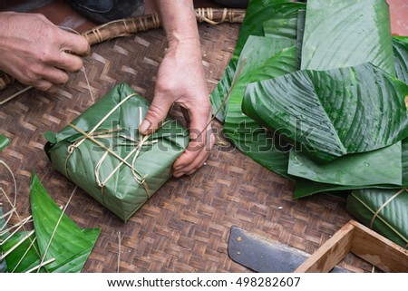 Hand wrapping Chung Cake in square shape with long node string split from bamboo. It is wrapped as tight as possible to keep cake from mold or spoiled. Traditional Vietnamese New Year (Tet) food.
