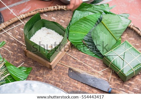 Chung Cake ingredients, tool preparation wrapping. Square shape wood mold with glutinous rice, split mung beans, chunks of pork shoulder, salt, pepper, ginger, bamboo, banana leaves, long node string.