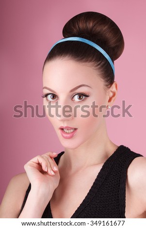 Portrait of lady with clean make-up and hair bun in the pink background in retro 60's style vintage