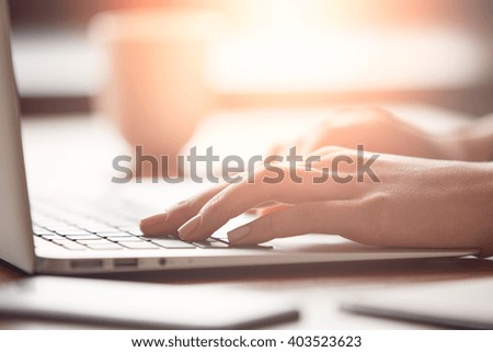 Cropped view of a female office worker relaxing in café after busy working day. Close-up of busy female hand typing on keyboard while sitting at her working place in the office