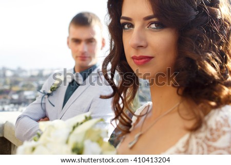 Portrait of the bride with lily bouquet while fince stands on the background - stock-photo-portrait-of-the-bride-with-lily-bouquet-while-fince-stands-on-the-background-410413204