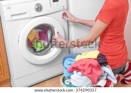 Woman loading the washing machine colored clothing.