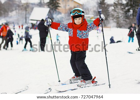 Little cute boy with skis and a ski outfit. Little skier in the ski resort