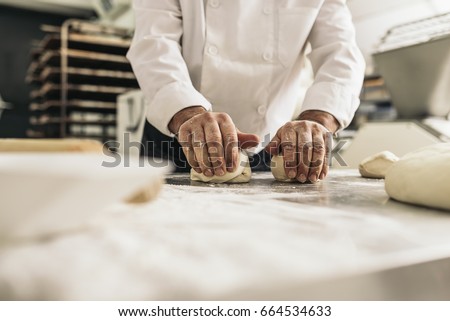 Baker kneading dough in a bakery. Bakery Concept.