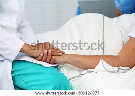 Friendly female medicine doctor hands holding pregnant woman's hand lying in bed for encouragement, empathy, cheering and support while medical examination. New life of abortion concept