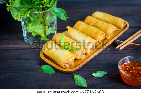 deep fried spring rolls in wooden tray with sauce place on black table