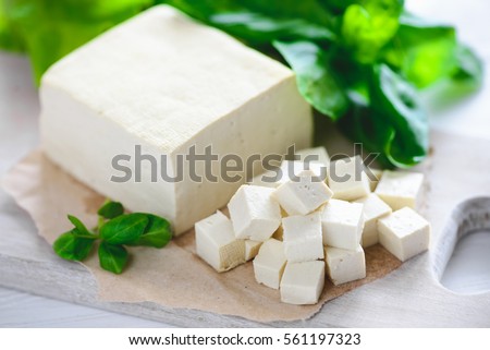soy cheese tofu diced on a cutting board, basil closeup