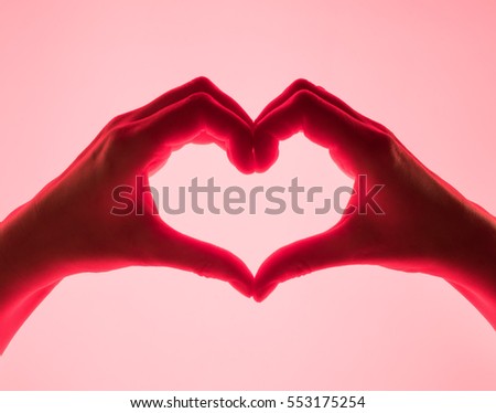 Hands in the form of heart red background. heart symbol with hand. valentines day card. Woman's hands silhouette in form of heart. hand Gestures