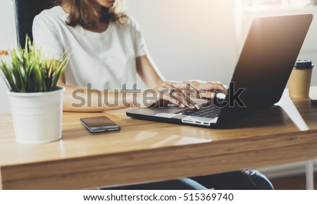 Cropped image of professional businesswoman working at her office via laptop, young female manager using portable computer device while sitting at modern loft, flare light, work process concept