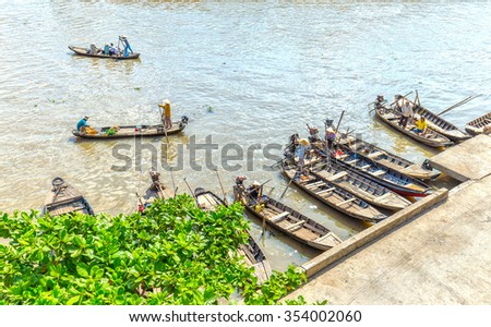 Hau Giang, Vietnam - April 6th, 2015: Wharf floating market with boats gathered waiting passenger, far away passenger barge across the river to go in the morning floating market in Hau Giang, Vietnam