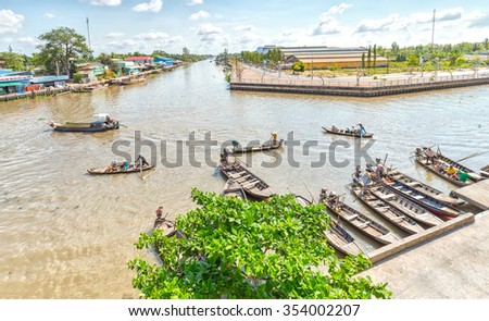 Hau Giang, Vietnam - April 6th, 2015: Panorama wharf floating market with boats gathered waiting passenger, far away passenger barge across river to go in floating market in Hau Giang, Vietnam