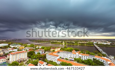 Hue, Vietnam - June 21st, 2015: City in the afternoon with billowing clouds when storm comes, below ancient red tile house as urban areas along river beautiful and idyllic in Hue, Vietnam