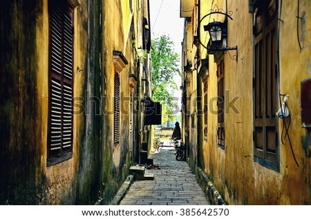 People passing between buildings in Hoi An, Vietnam (Movie color tone)