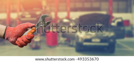 Car repairing,Hand of technician auto mechanic with a wrench working in garage. service in auto repair station.vintage tone,for banner