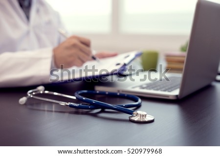 Stethoscope with clipboard and Laptop on desk,Doctor working in hospital writing a prescription, Healthcare and medical concept,test results in background,vintage color,selective focus