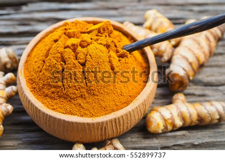 Turmeric powder in bowls and fresh turmeric on old wooden background. herbal