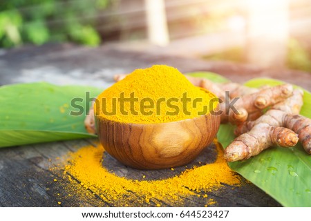 Turmeric powder and fresh turmeric in wooden bowls on old wooden table. herbal