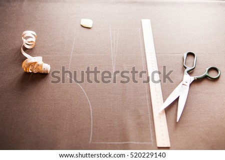 Still life photo of a suit pattern template with tape measure, chalk and scissors. Sewing and tailoring tools and accesories.