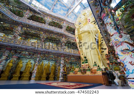 NHA TRANG, VIETNAM - JUNE 23, 2016: Big gold statue of Buddha in the temple. Internal furniture of the Buddhist church. Walls are painted with multi-colored drawings.